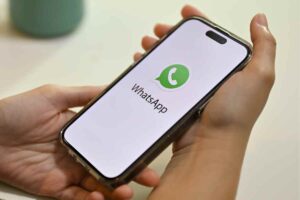 mani reggono uno smatphone con logo whatsApp